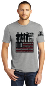 A man in a gray t-shirt featuring silhouettes and an American flag design with the text 'WWTR Blue Skies Family.